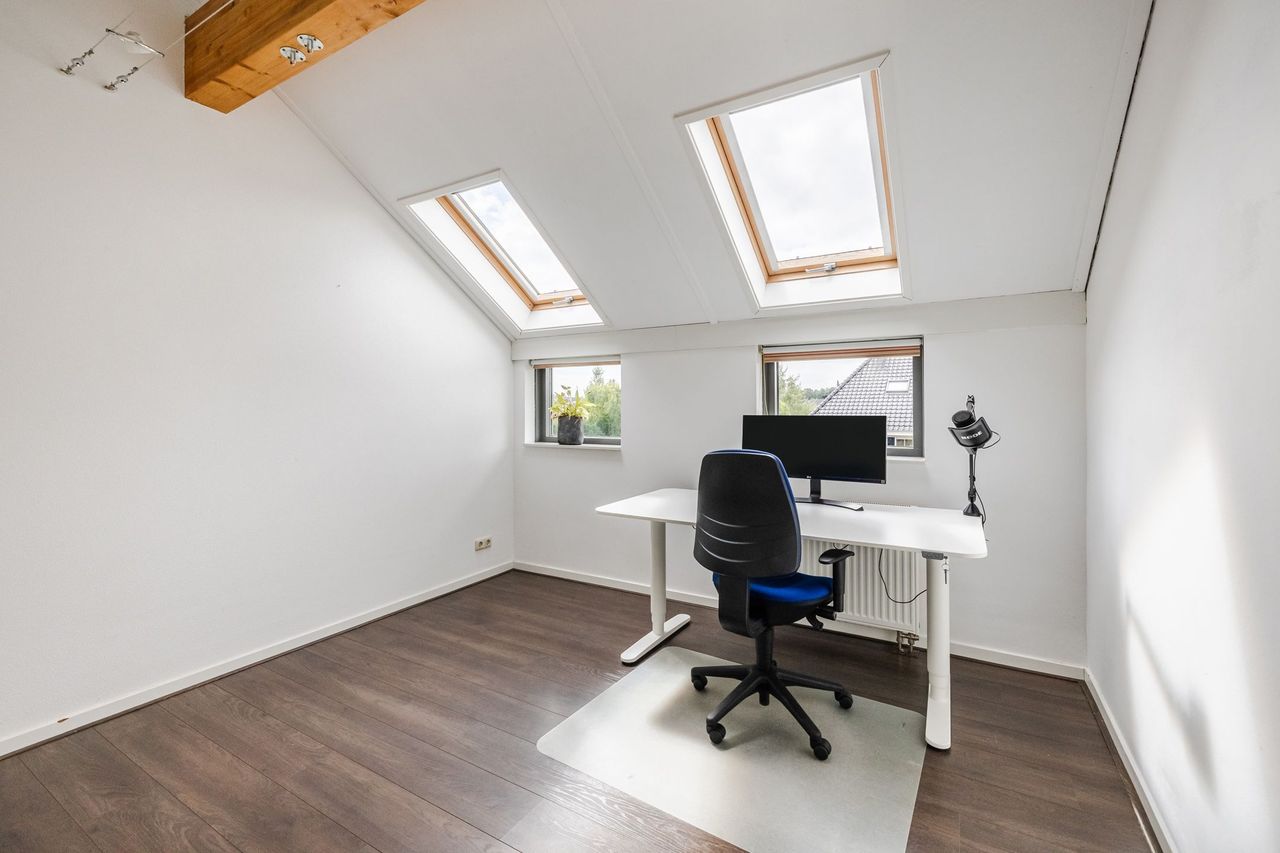 Zolderkamer in gebruik als werkkamer, met bureau onder de dakramen
