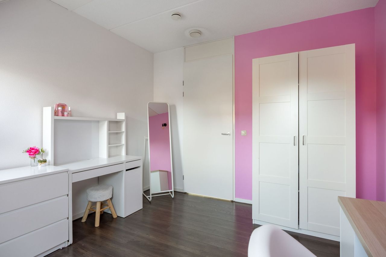 Slaapkamer met bureau, passpiegel en een ruime kledingkast tegen de accentwand