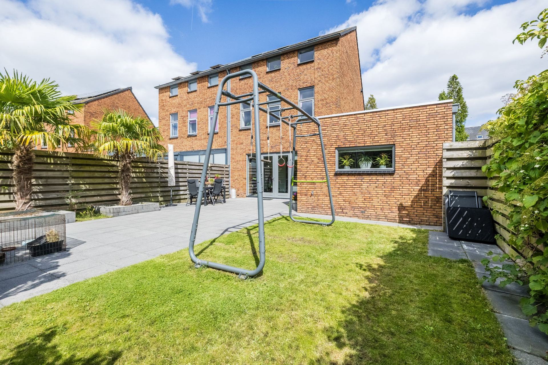 De achtertuin op het westen, met gazon, palmen en de achtergevel van de woning