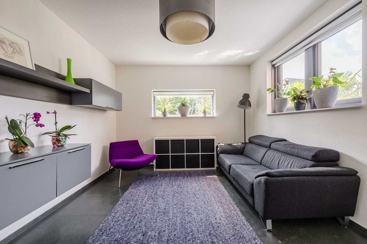 De extra leefruimte op de begane grond, met bank, dressoir en twee ramen